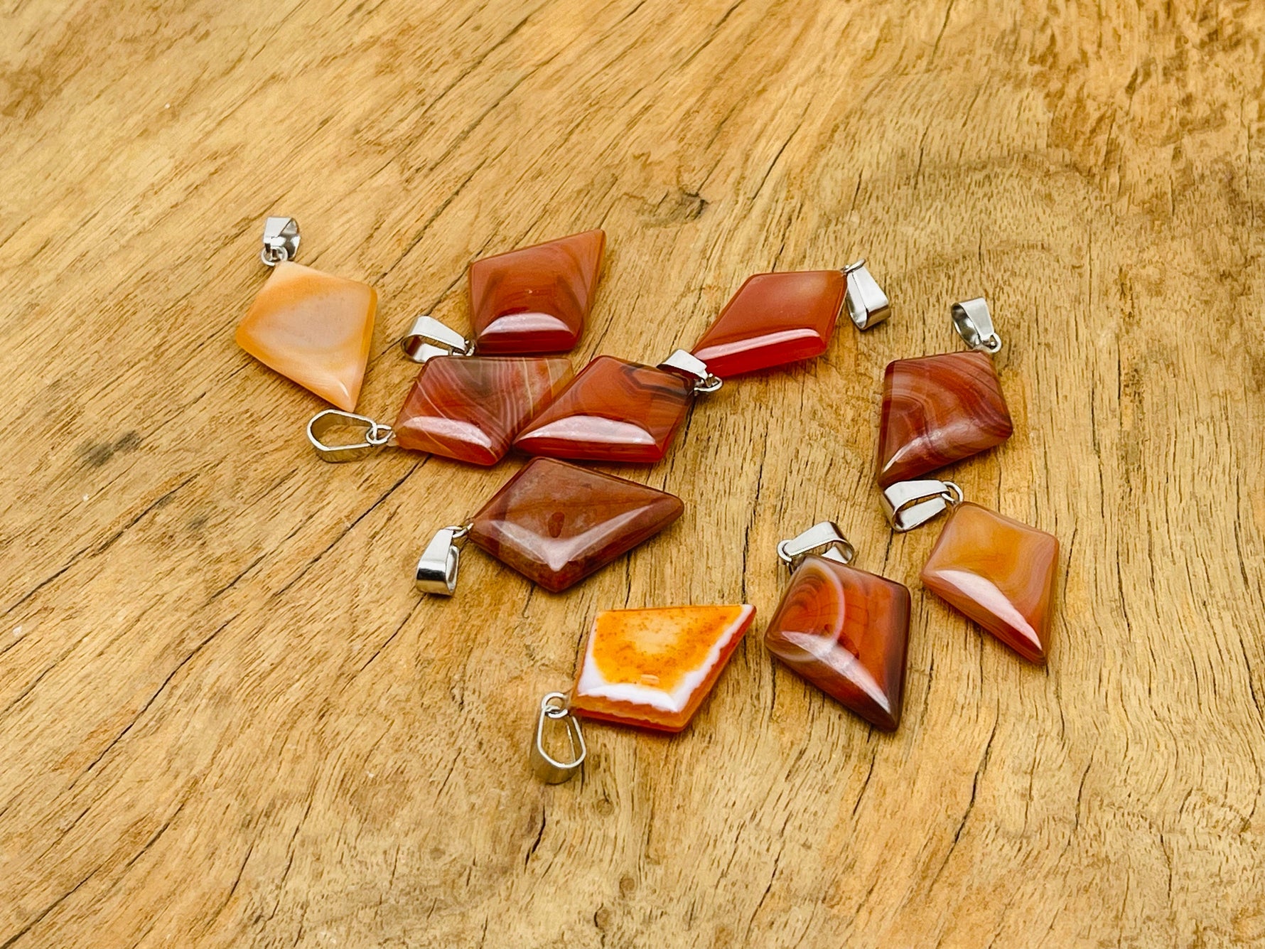 Carnelian triangle gemstone pendant by GemstoneGO featuring a geometric design and polished orange-red stone.