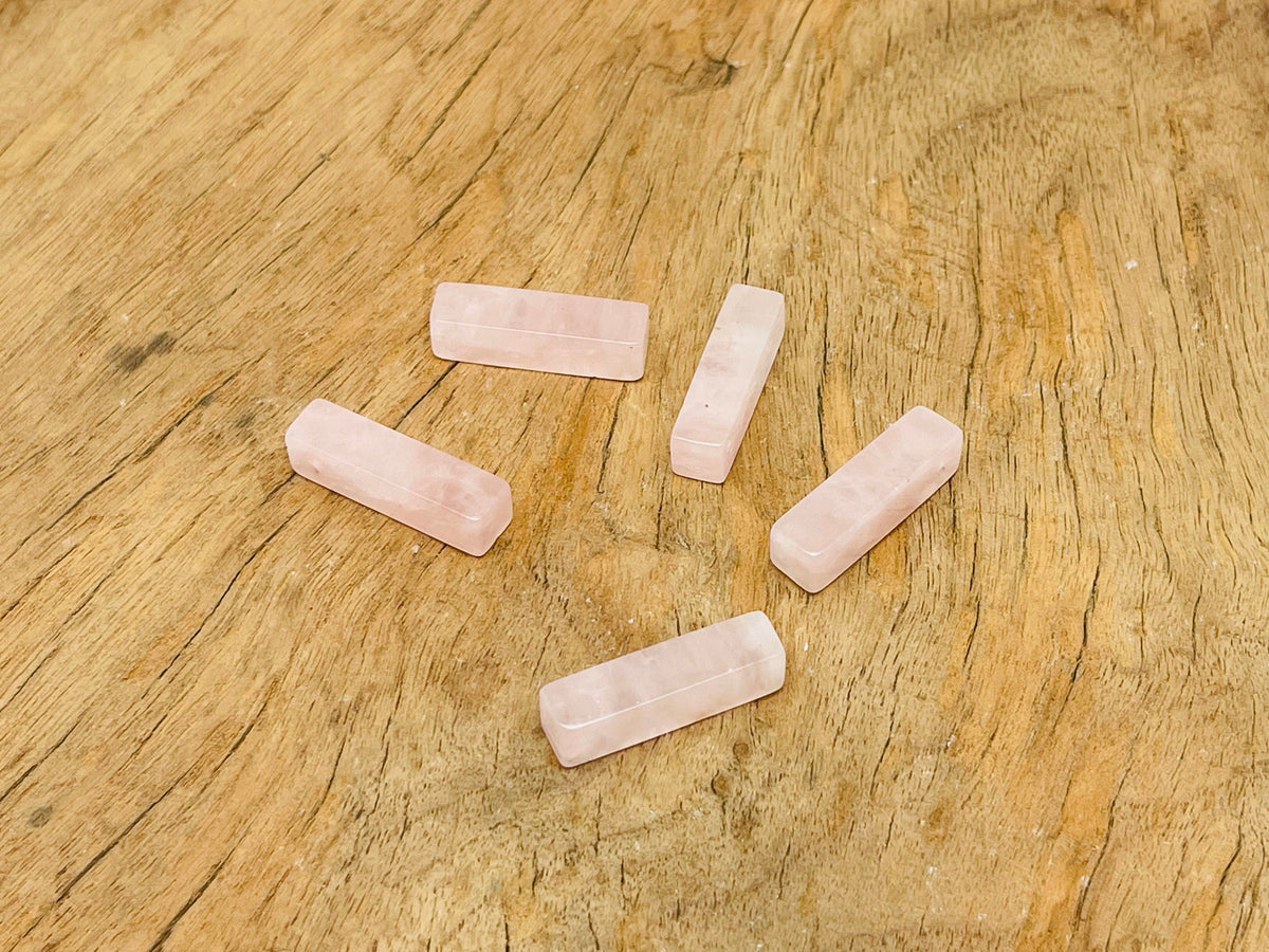 Rose quartz crystal pendant from GemstoneGO, drilled gemstone for jewelry making, showcasing a smooth pink stone on a clear background.