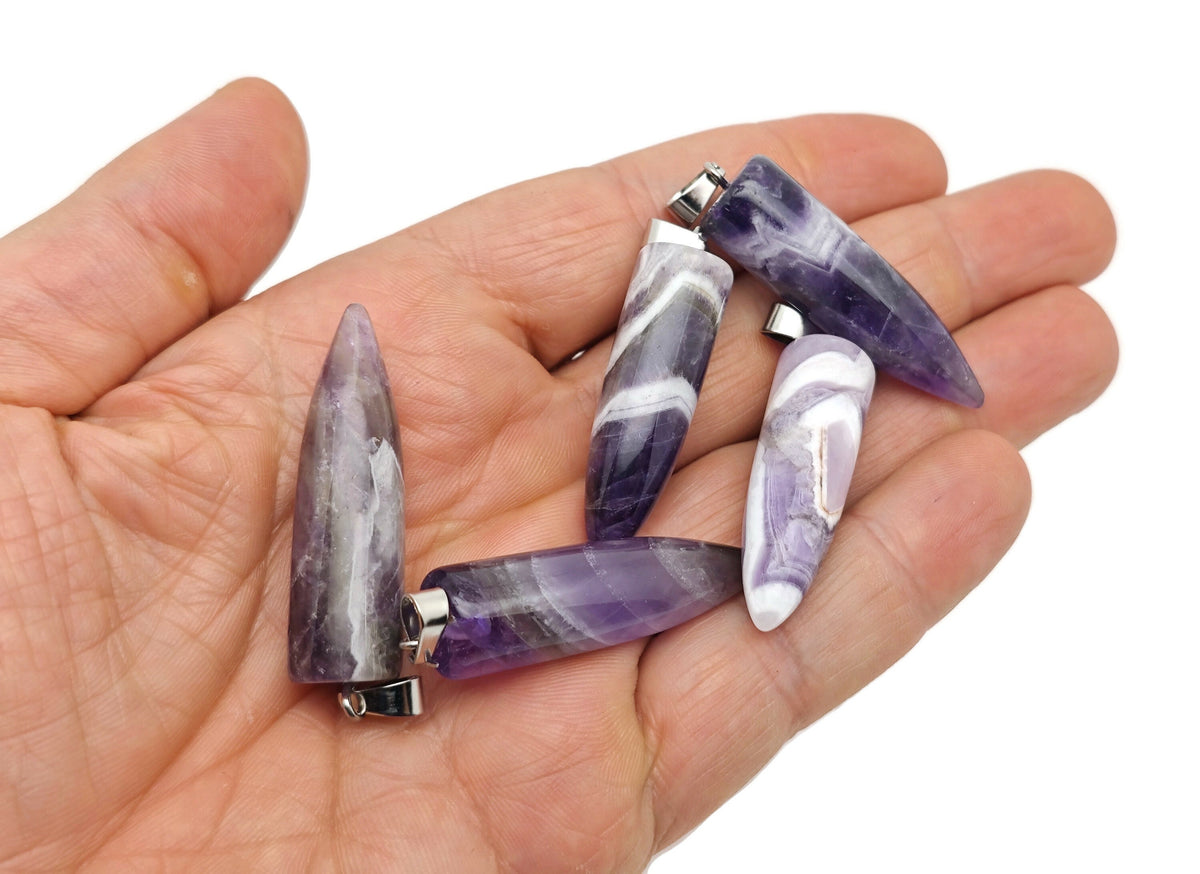 Polished amethyst bullet gemstone pendant with carved design, showcasing vibrant purple color and smooth, glossy surface.