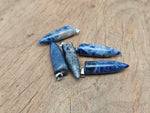 Polished sodalite bullet gemstone pendant with carved details, showcasing deep blue and white natural stone patterns.