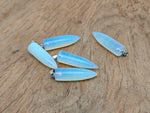 Polished opalite bullet gemstone pendant with carved details, showcasing smooth, reflective surface and natural stone beauty.