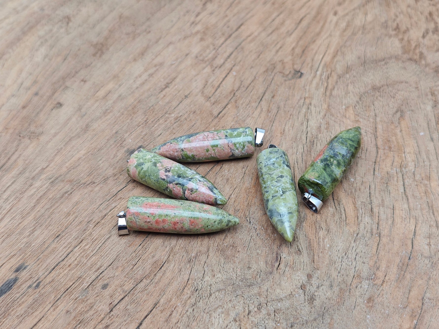 Polished Unakite bullet gemstone pendant with carved details, featuring earthy green and pink tones, from GemstoneGO.