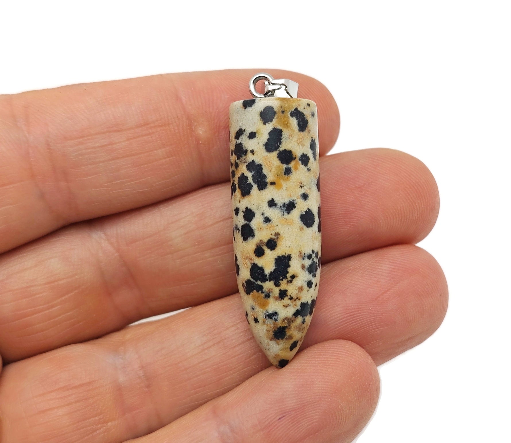 Polished Dalmatian Jasper bullet gemstone pendant with carved details, showcasing natural black spots on a cream-colored stone.