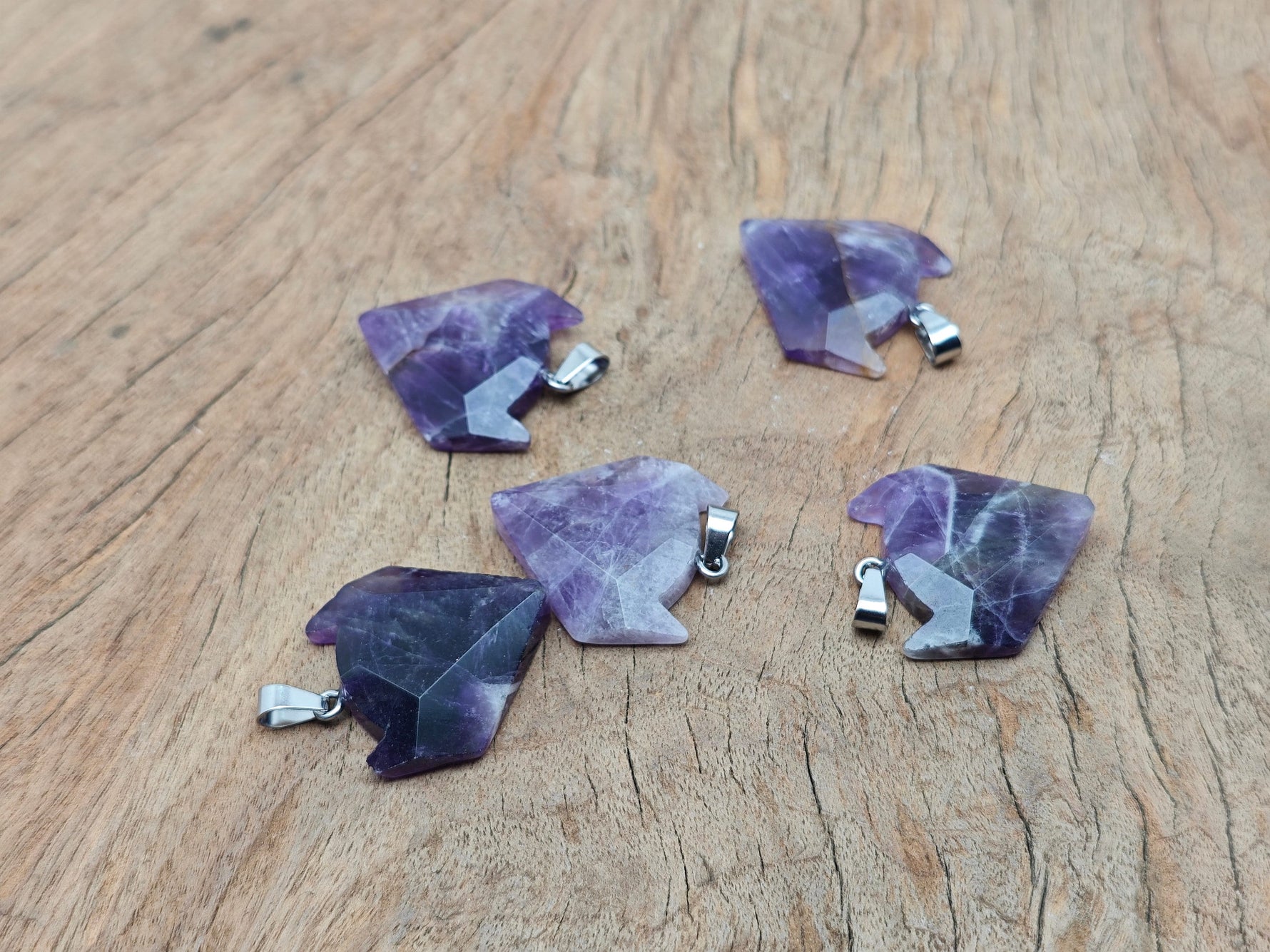 Amethyst gemstone wolf head pendant with detailed carvings, hanging from a silver chain, showcasing crystal jewelry craftsmanship.
