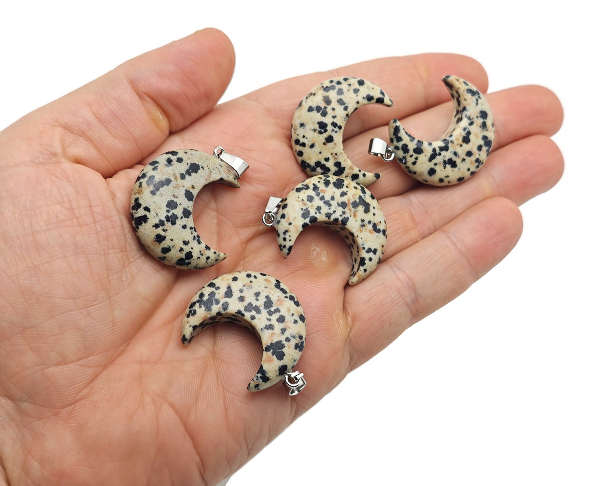 Dalmatian Jasper moon gemstone pendant featuring a crescent moon shape from GemstoneGO, showcasing black spots on a cream background.