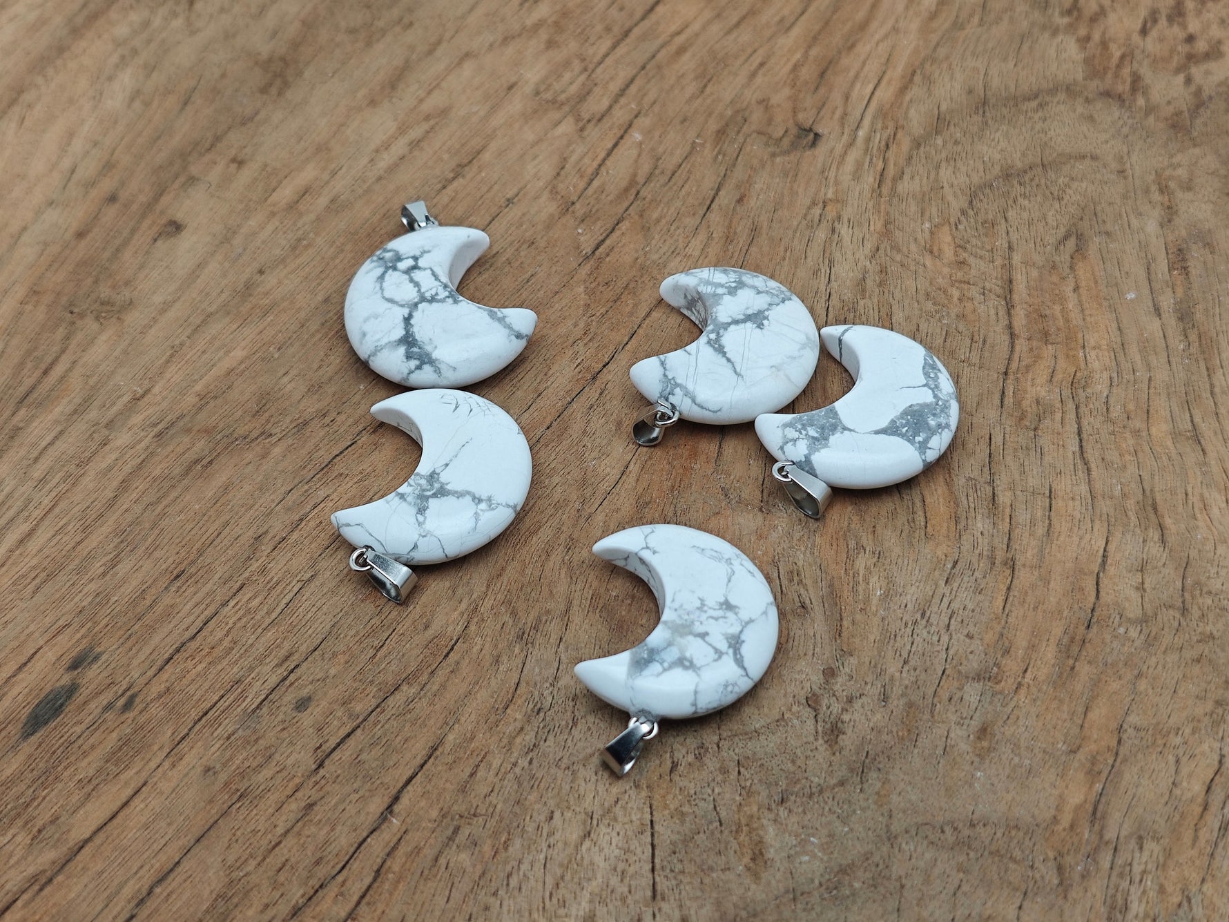 Howlite moon gemstone pendant featuring a crescent moon design by GemstoneGO, showcasing a polished white stone with gray veining.