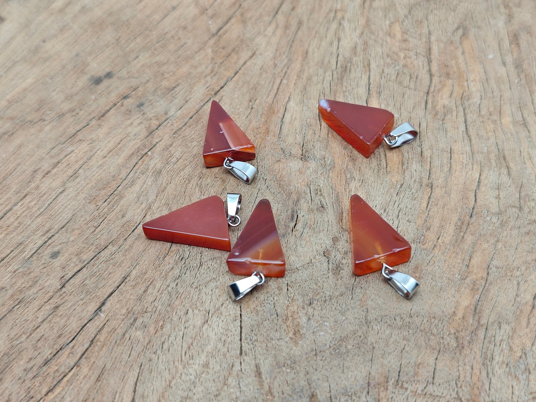 Carnelian triangle-shaped crystal pendant from GemstoneGO, showcasing vibrant orange gemstone with polished smooth surface.