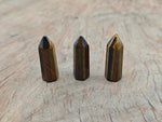 Tiger Eye obelisk tower crystal, 40mm, from GemstoneGO, showing polished brown and golden hues with natural stone patterns.