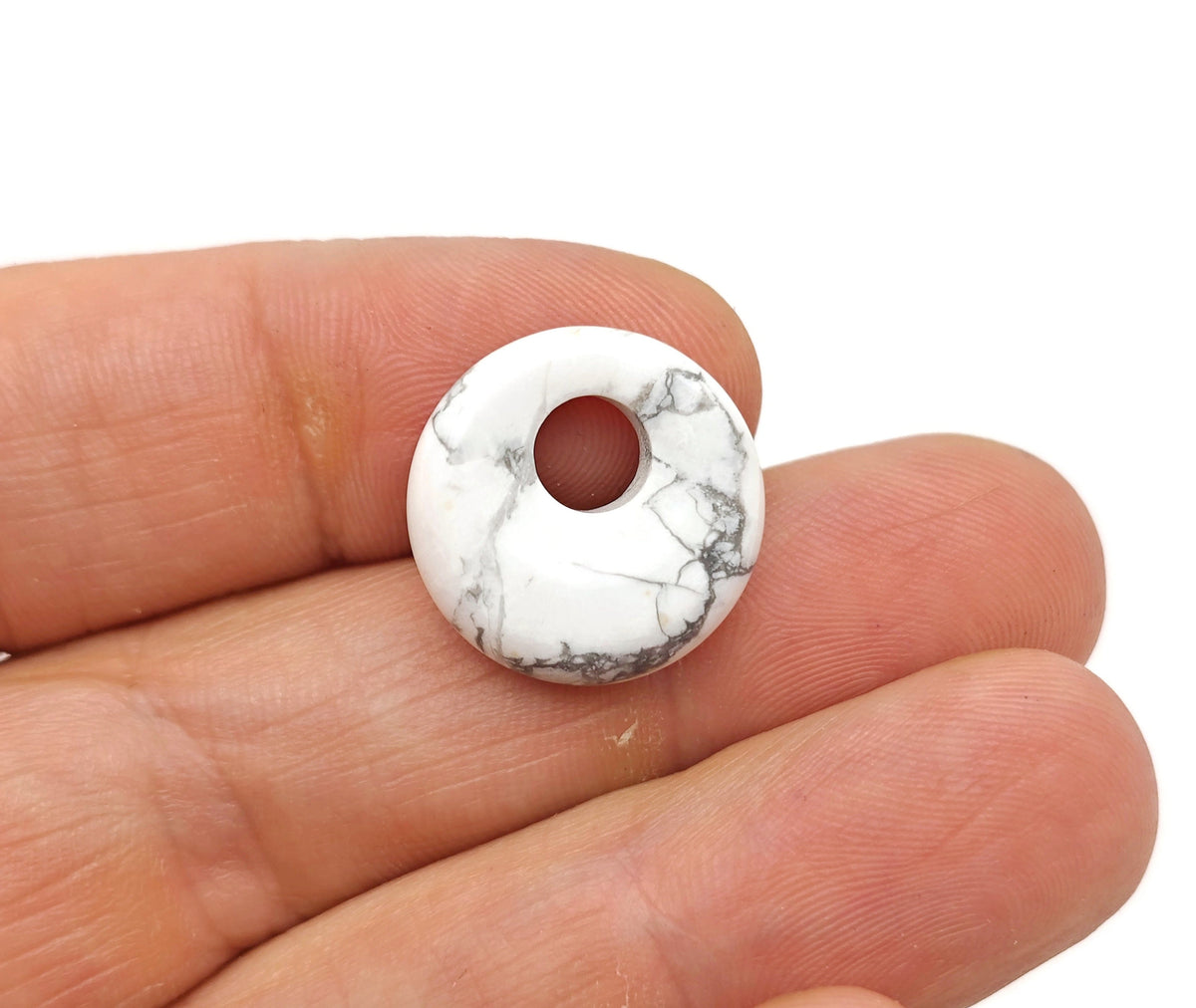 Howlite crystal donut pendant, 18mm Pi Stone from GemstoneGO, showcasing smooth white gemstone with gray veining and polished finish.