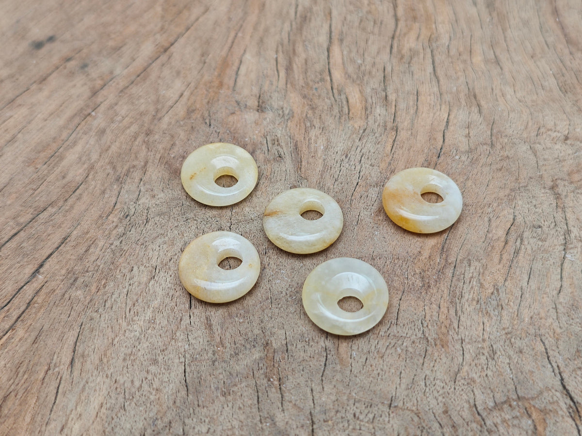 Yellow jade crystal donut pendant, 18mm Pi stone from GemstoneGO, showcasing a smooth, polished yellow jade gemstone with a donut shape.