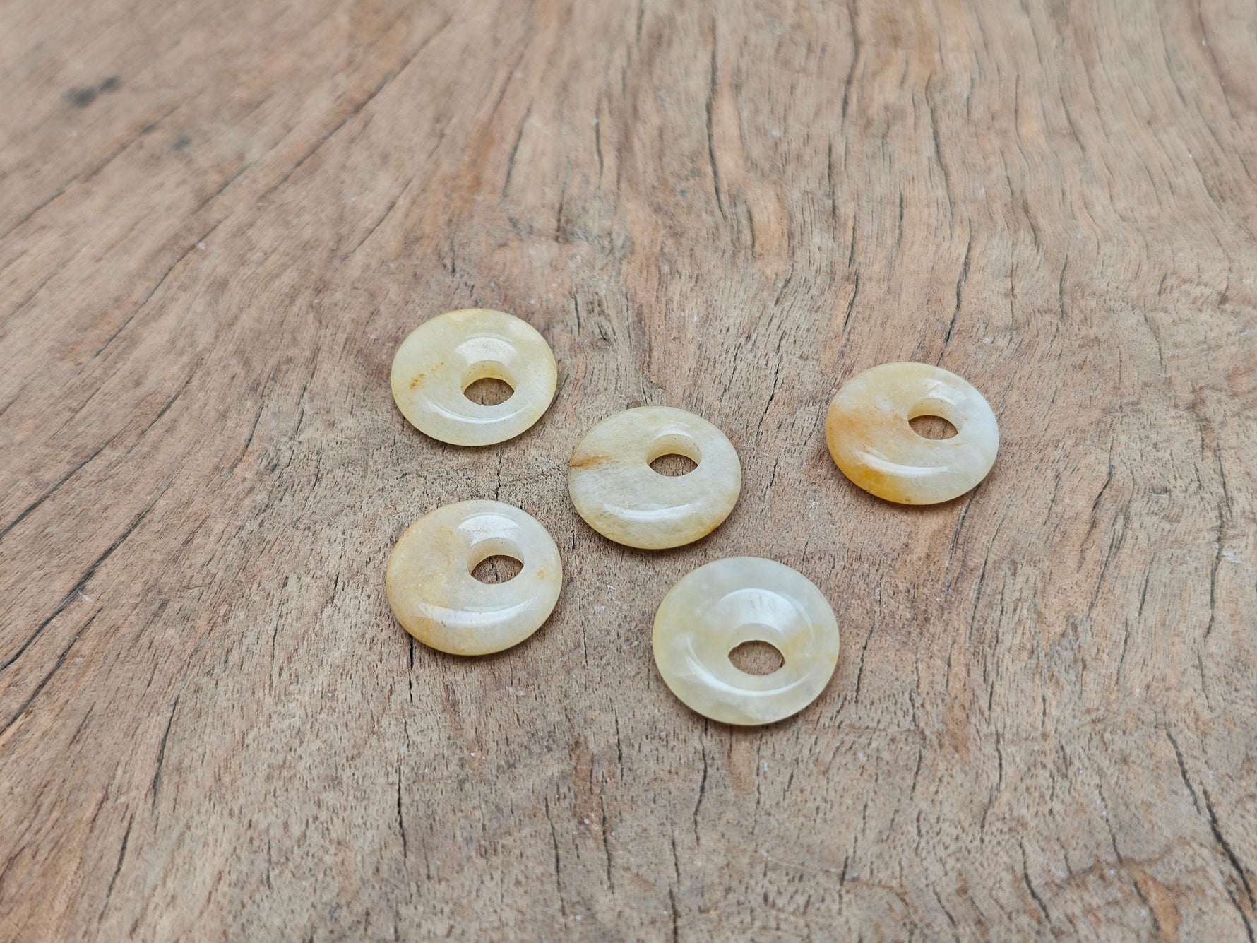 Yellow jade crystal donut pendant, 18mm Pi stone from GemstoneGO, showcasing a smooth, polished yellow jade gemstone with a donut shape.