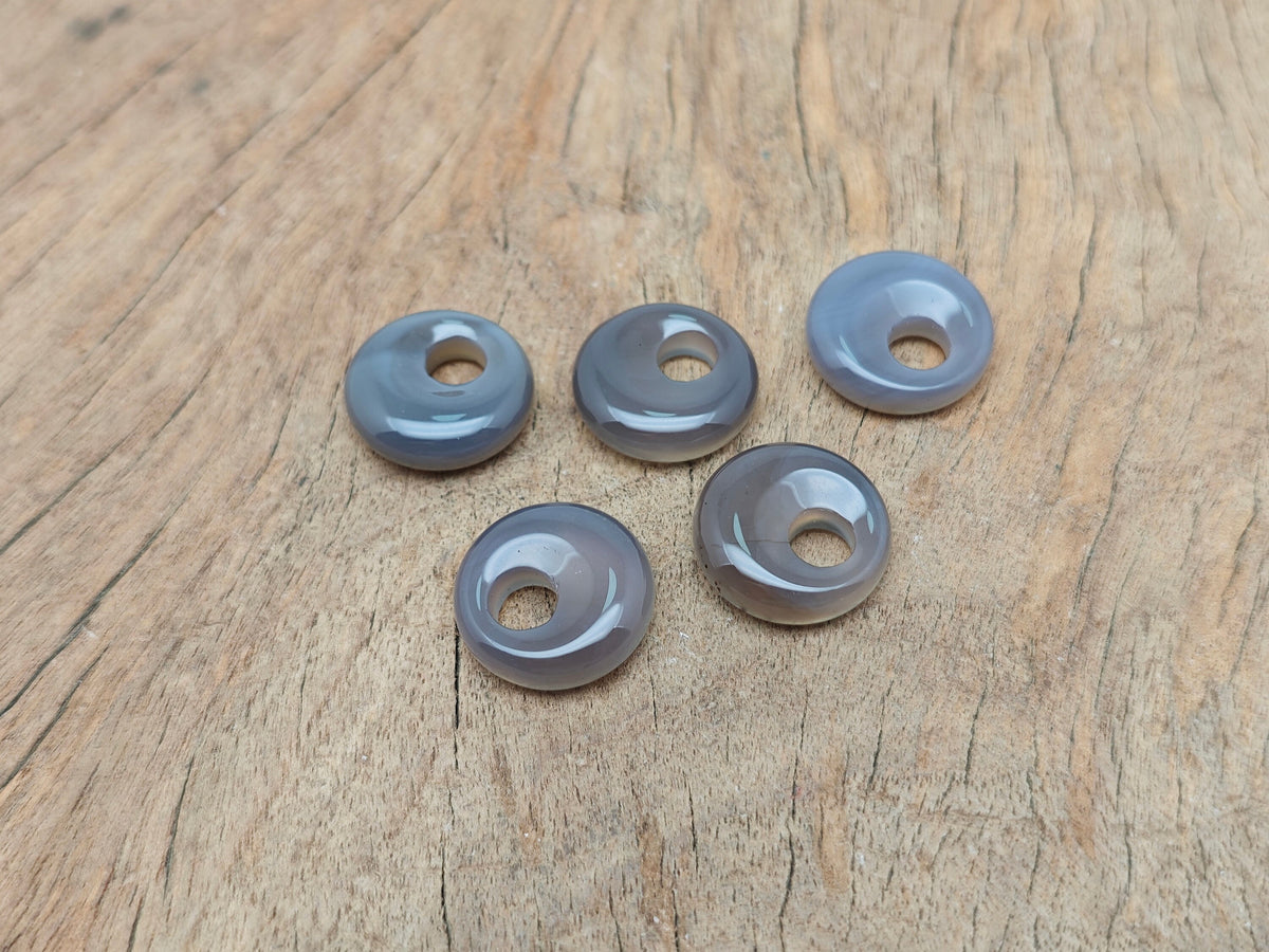 Grey agate crystal donut pendant from GemstoneGO, 18mm Pi stone with polished surface, showcasing natural stone patterns.