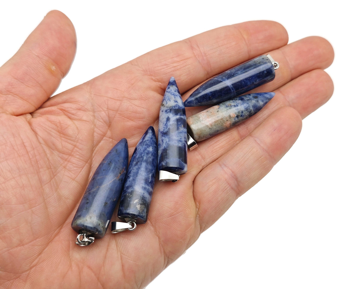 Polished sodalite bullet gemstone pendant with carved design, showcasing a smooth, deep blue gemstone on a neutral background.