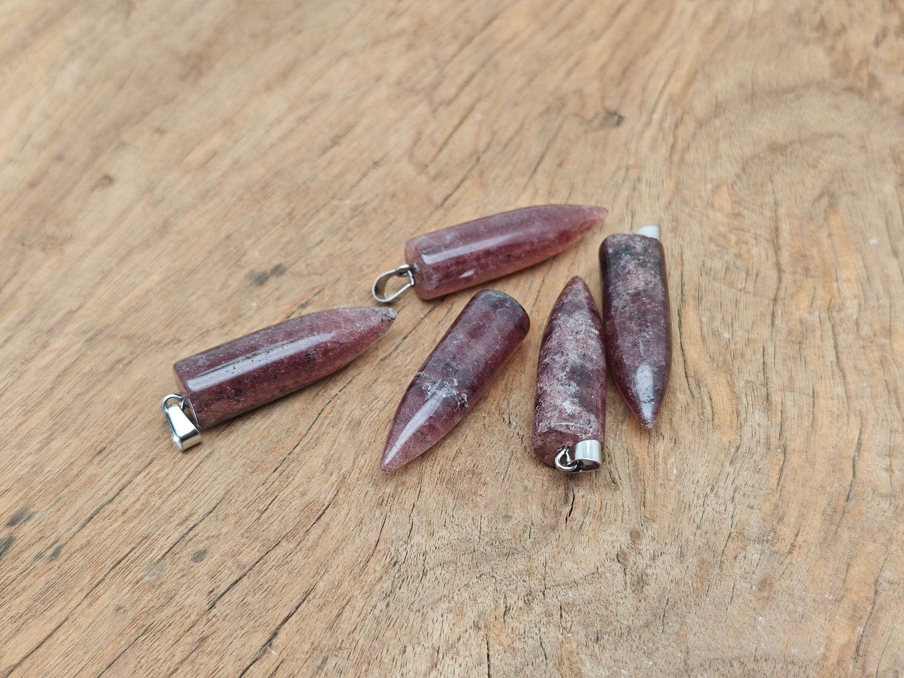 Polished strawberry quartz bullet gemstone pendant with carved details, showcasing a smooth, vibrant pink pendant on a silver chain.