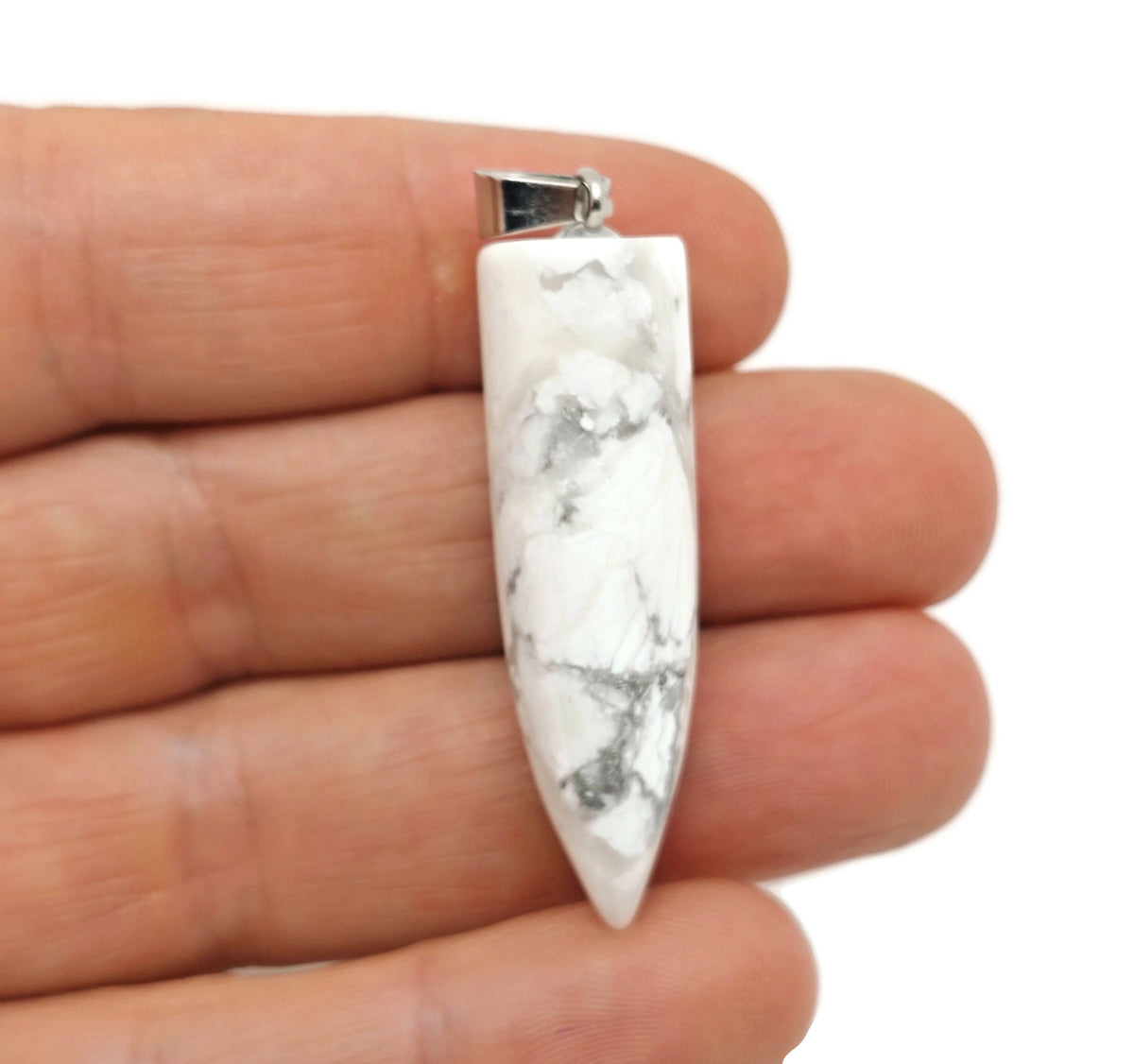 Polished Howlite bullet gemstone pendant with carved details, showcasing smooth, white, and gray marbled stone on a plain background.