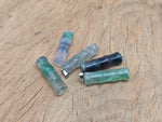 Fluorite crystal pendant in bamboo shape with protective energy, crafted by GemstoneGO, showcasing vibrant purple and green hues.