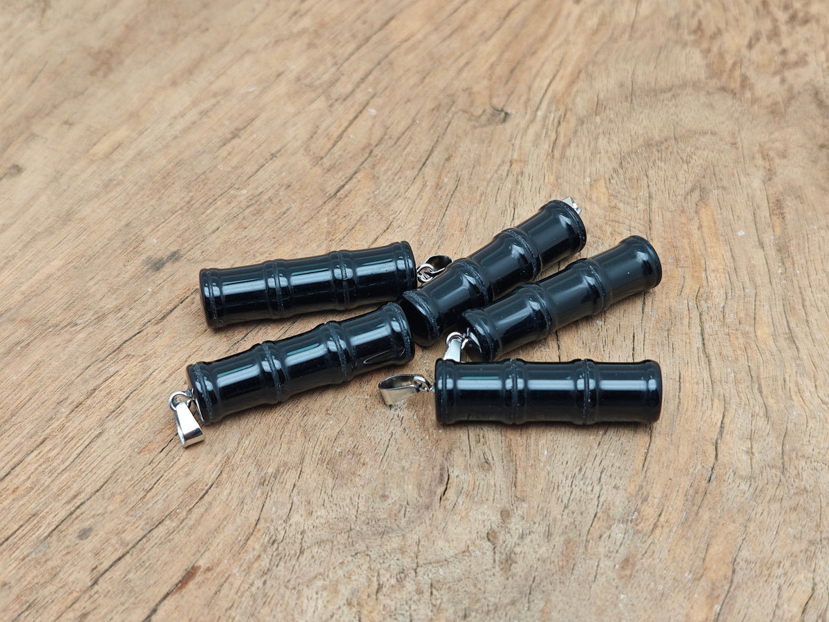 Obsidian bamboo-shaped crystal pendant with protective energy, featuring a black polished gemstone on a silver chain.