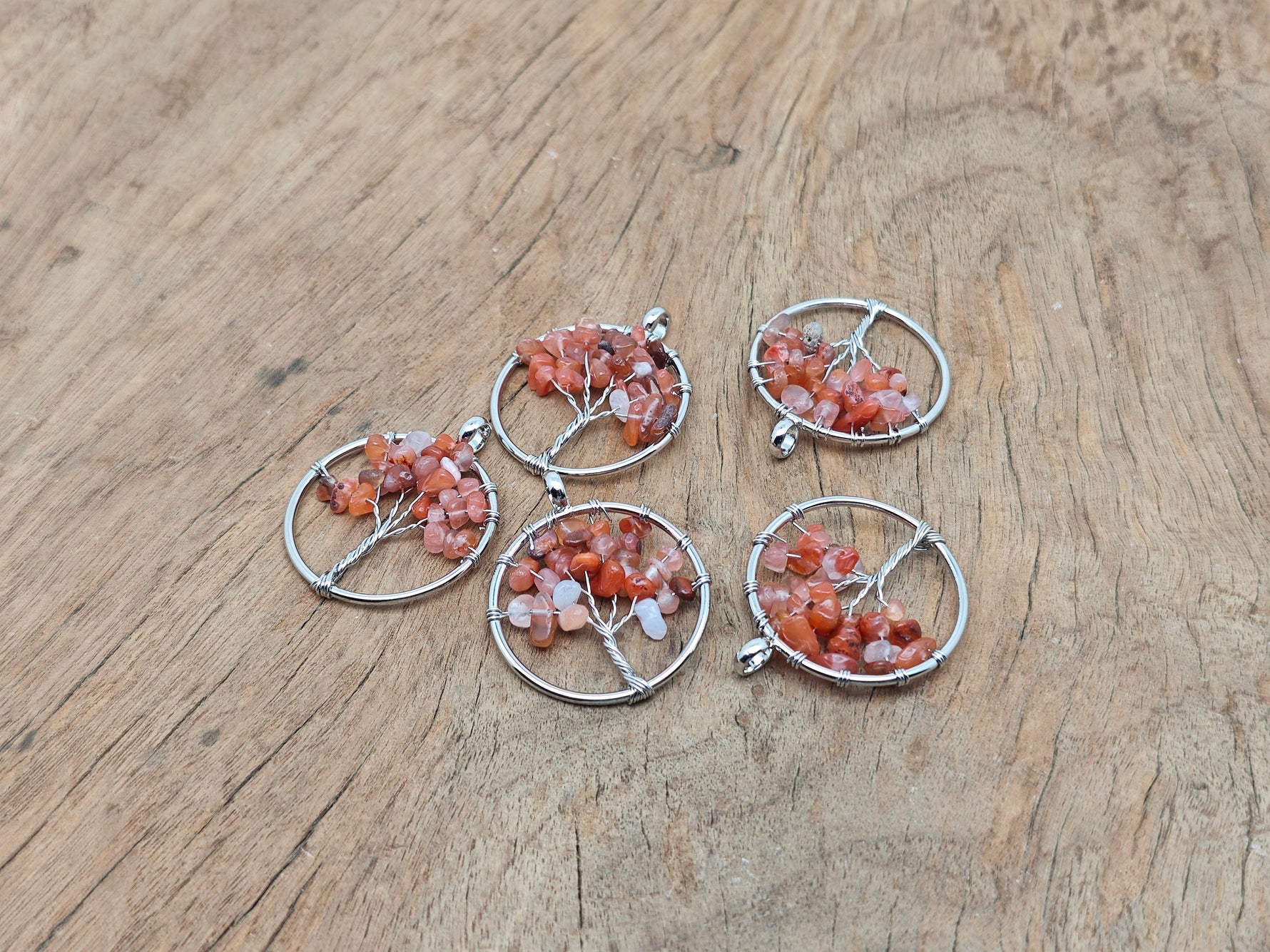 Carnelian Tree of Life gemstone pendant with intricate design, featuring vibrant orange-red carnelian stones and detailed metalwork.