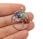Seven Chakra Tree of Life gemstone pendant with colorful crystals on a silver setting, displayed against a neutral background.