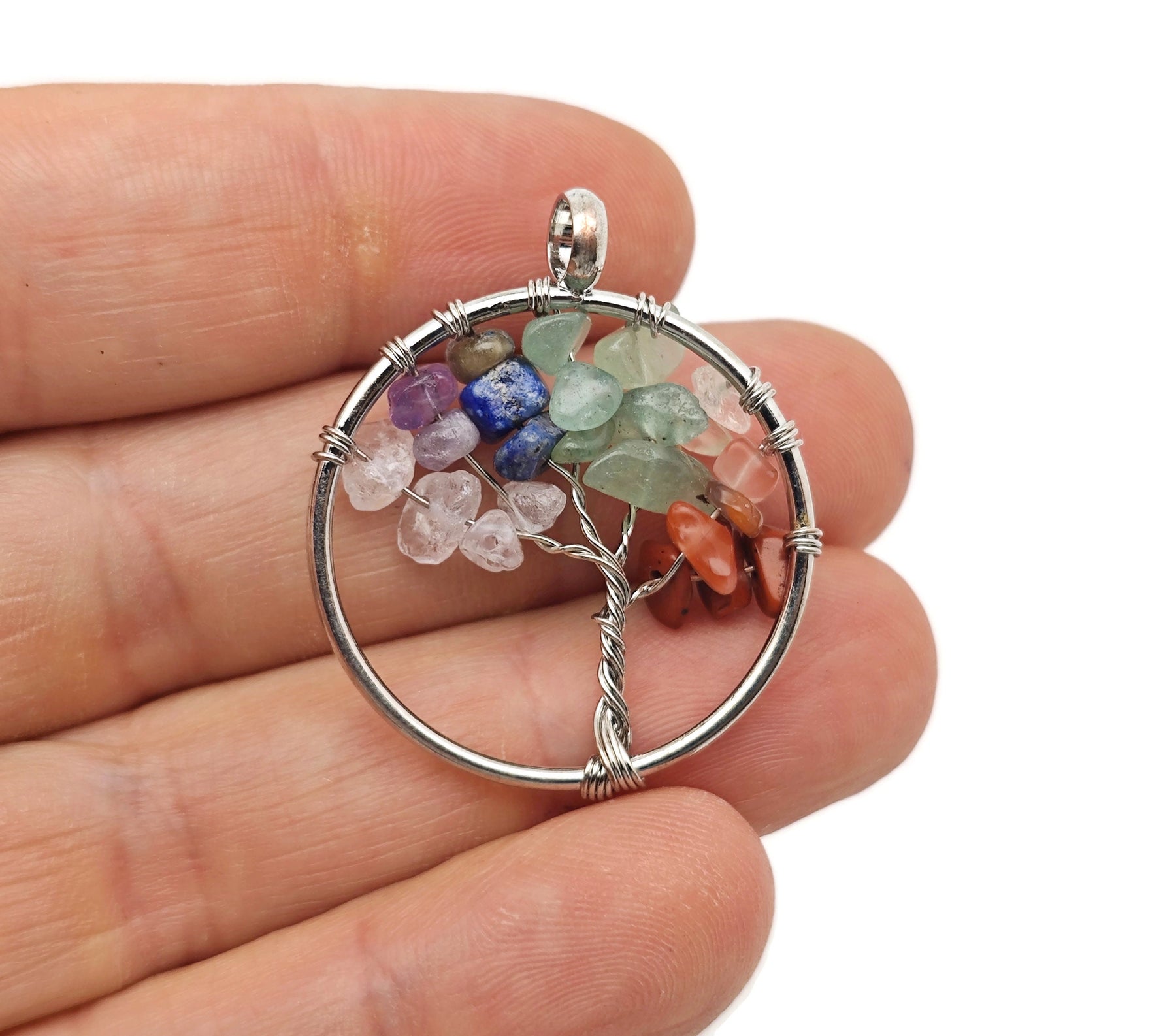 Seven Chakra Tree of Life gemstone pendant with colorful crystals on a silver setting, displayed against a neutral background.