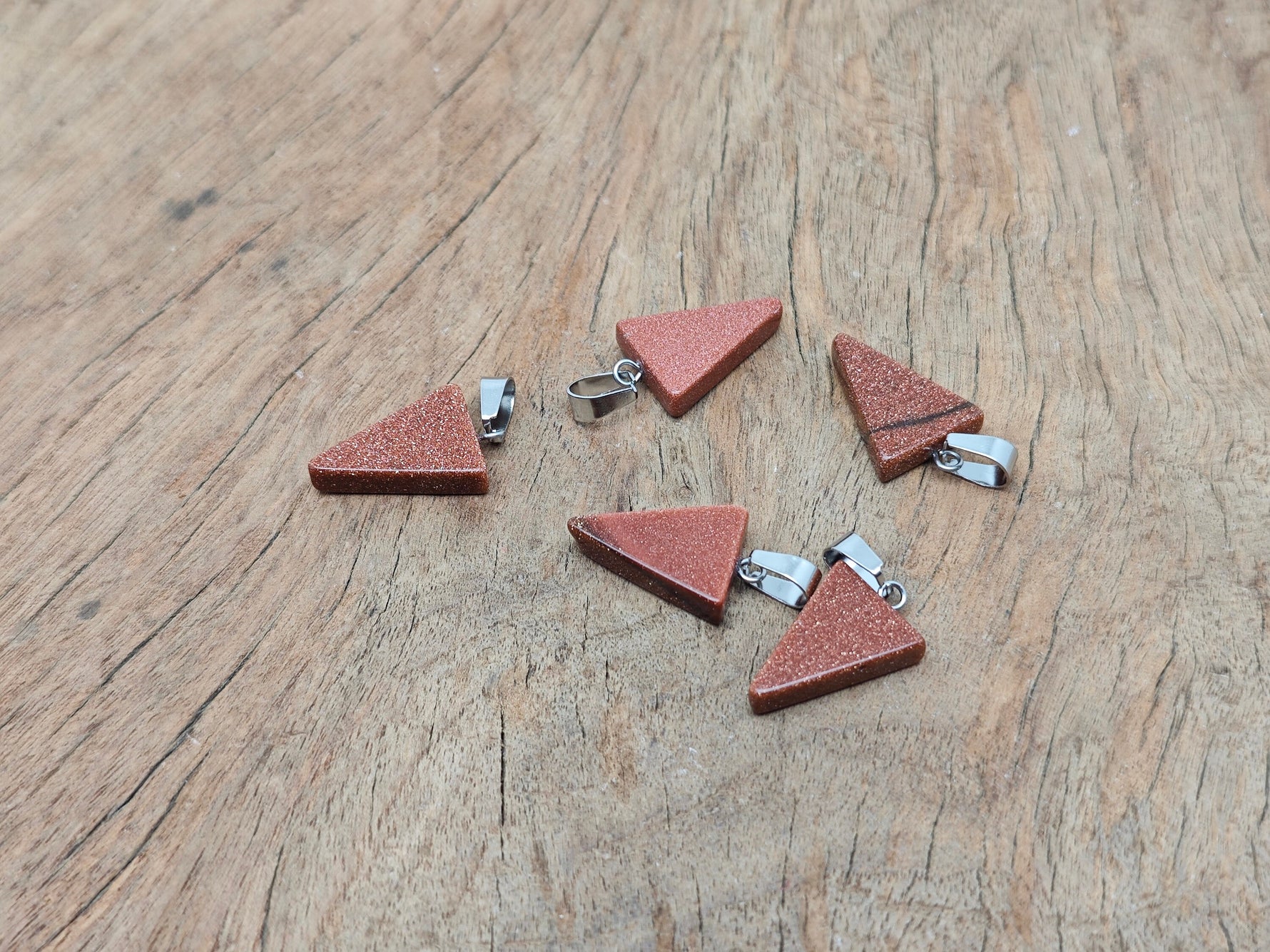 Goldstone triangle-shaped crystal pendant from GemstoneGO, showing its sparkling gold-toned glass and faceted design.