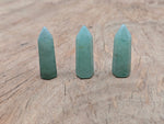 Aventurine obelisk tower crystal from GemstoneGO, 40mm tall, with green gemstone facets and pointed top on a white background.