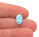 Larimar crystal pendant with gold setting from GemstoneGO, showcasing a smooth, oval-shaped blue gemstone pendant on a chain.