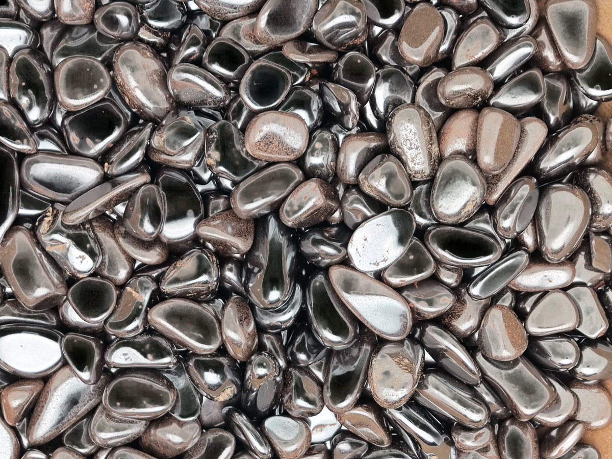 Semi-tumbled hematite crystal chips in 7-12mm, shown in bulk, with a smooth, metallic gray appearance and natural gemstone texture.