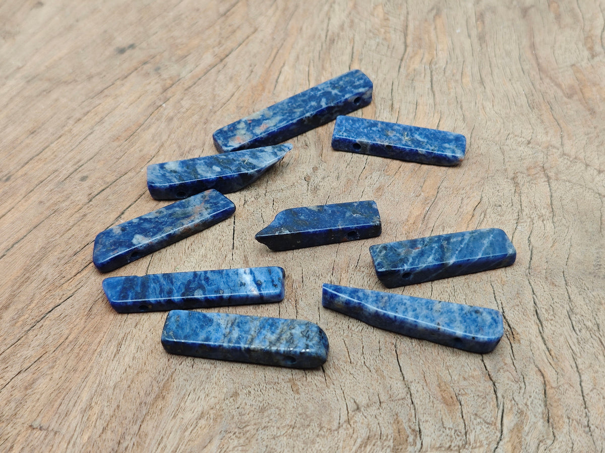 Drilled sodalite gemstone pendant from GemstoneGO, showcasing a deep blue, polished tumbled stone with natural patterns and a drilled hole.