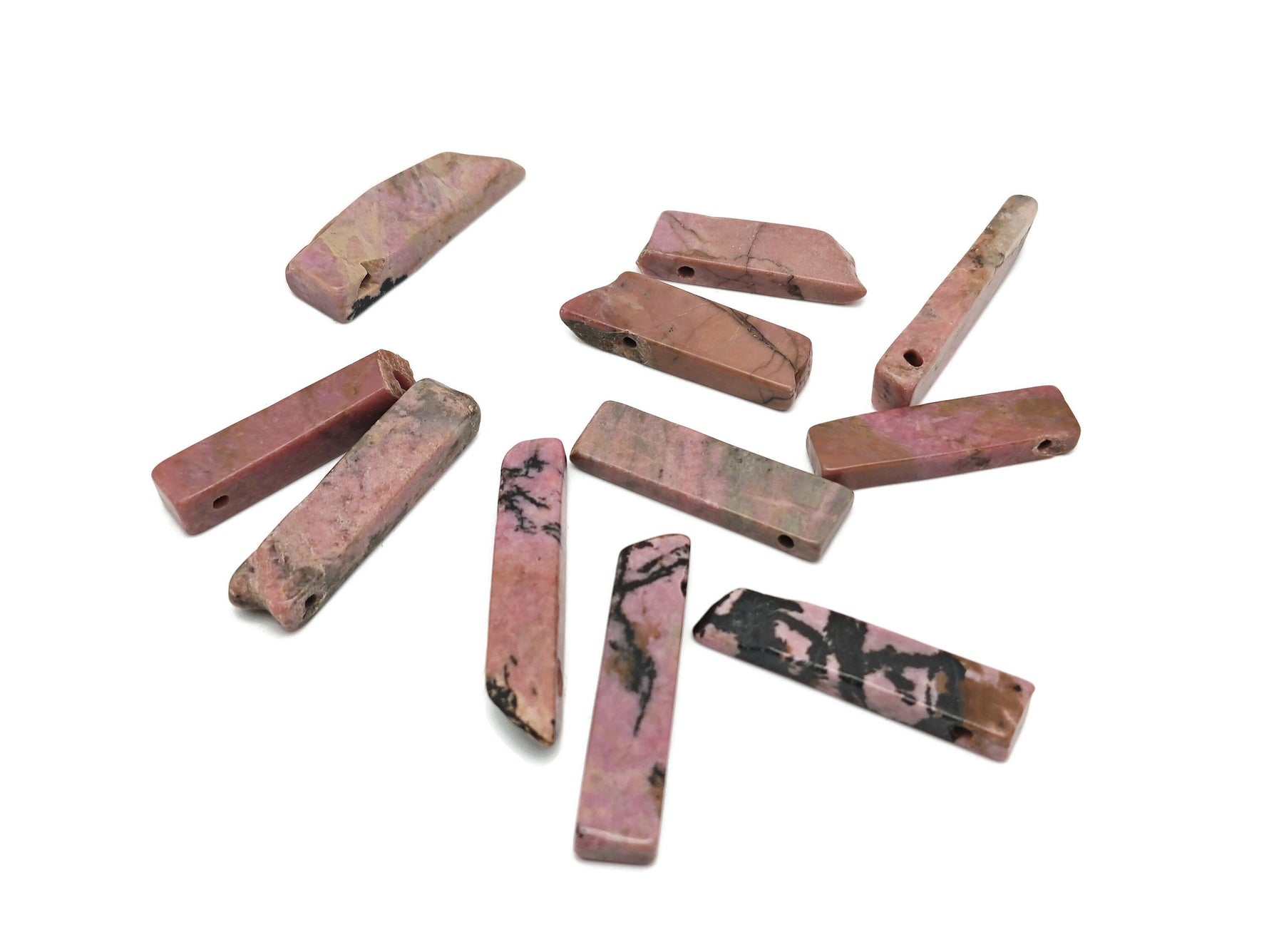 Rhodonite drilled tumbled gemstone pendant from GemstoneGO, showcasing a smooth pink and black patterned stone with a drilled hole for jewelry.