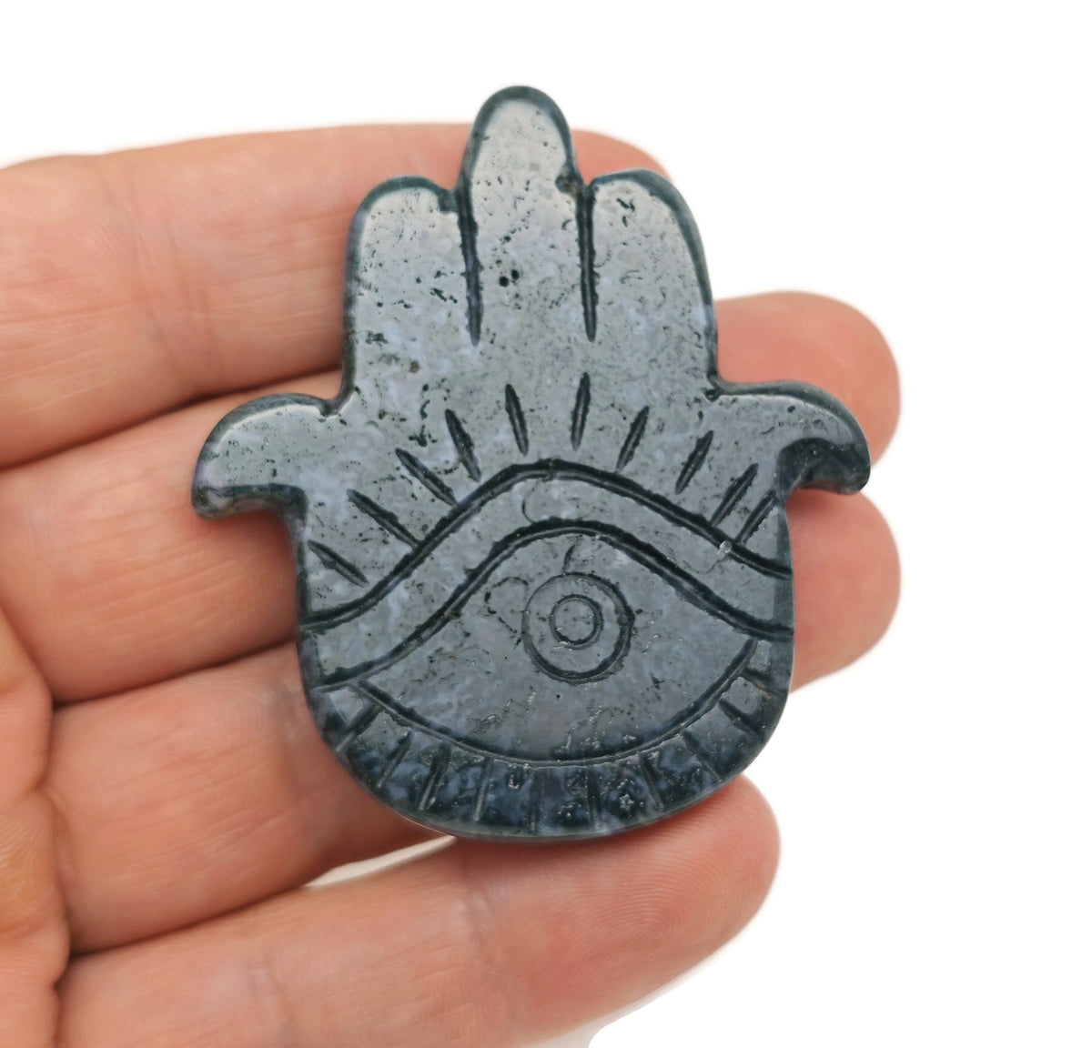 Moss agate evil eye gemstone carving held in hand, detailed hand-carved evil eye talisman from GemstoneGO.