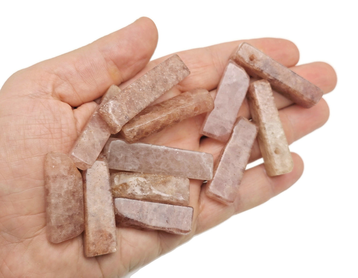 Strawberry quartz drilled tumbled gemstone pendant from GemstoneGO featuring a vibrant pink, polished stone with a hole for jewelry.
