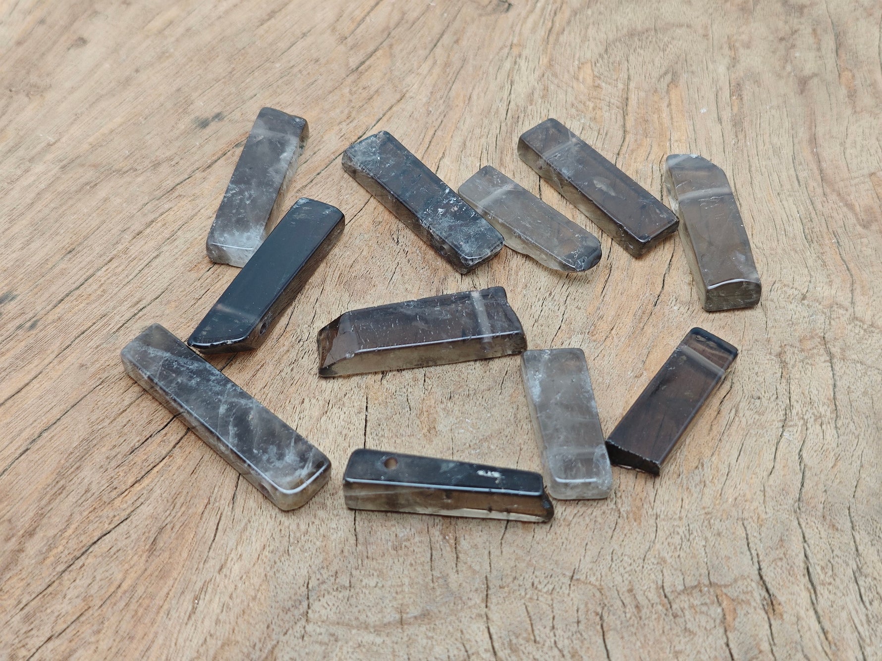 Smoky Quartz drilled tumbled gemstone pendant from GemstoneGO, showcasing a smooth, polished, brownish-gray stone with a hole for jewelry.