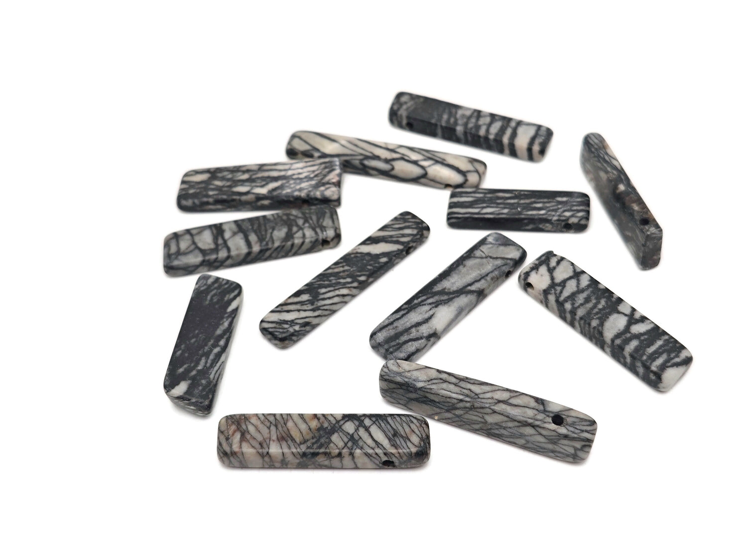 Black Network Jasper drilled tumbled gemstone pendant from GemstoneGO, showcasing a smooth, polished black and gray patterned stone.