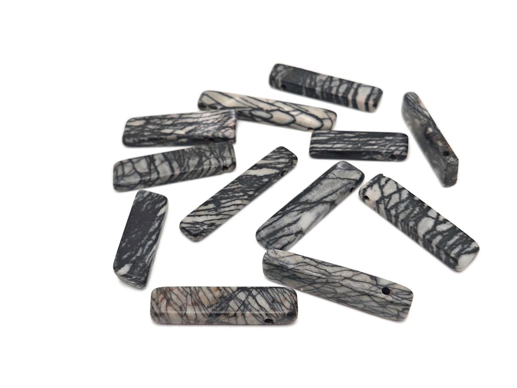 Black Network Jasper drilled tumbled gemstone pendant from GemstoneGO, showcasing a smooth, polished black and gray patterned stone.