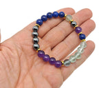 Handmade root chakra gemstone bracelet featuring colorful beads and a silver clasp, designed for balancing energy and intention.