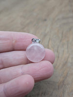 Rose quartz flat round gemstone pendant with a crystal coin design, showcasing a smooth, polished pink gemstone on a silver setting.