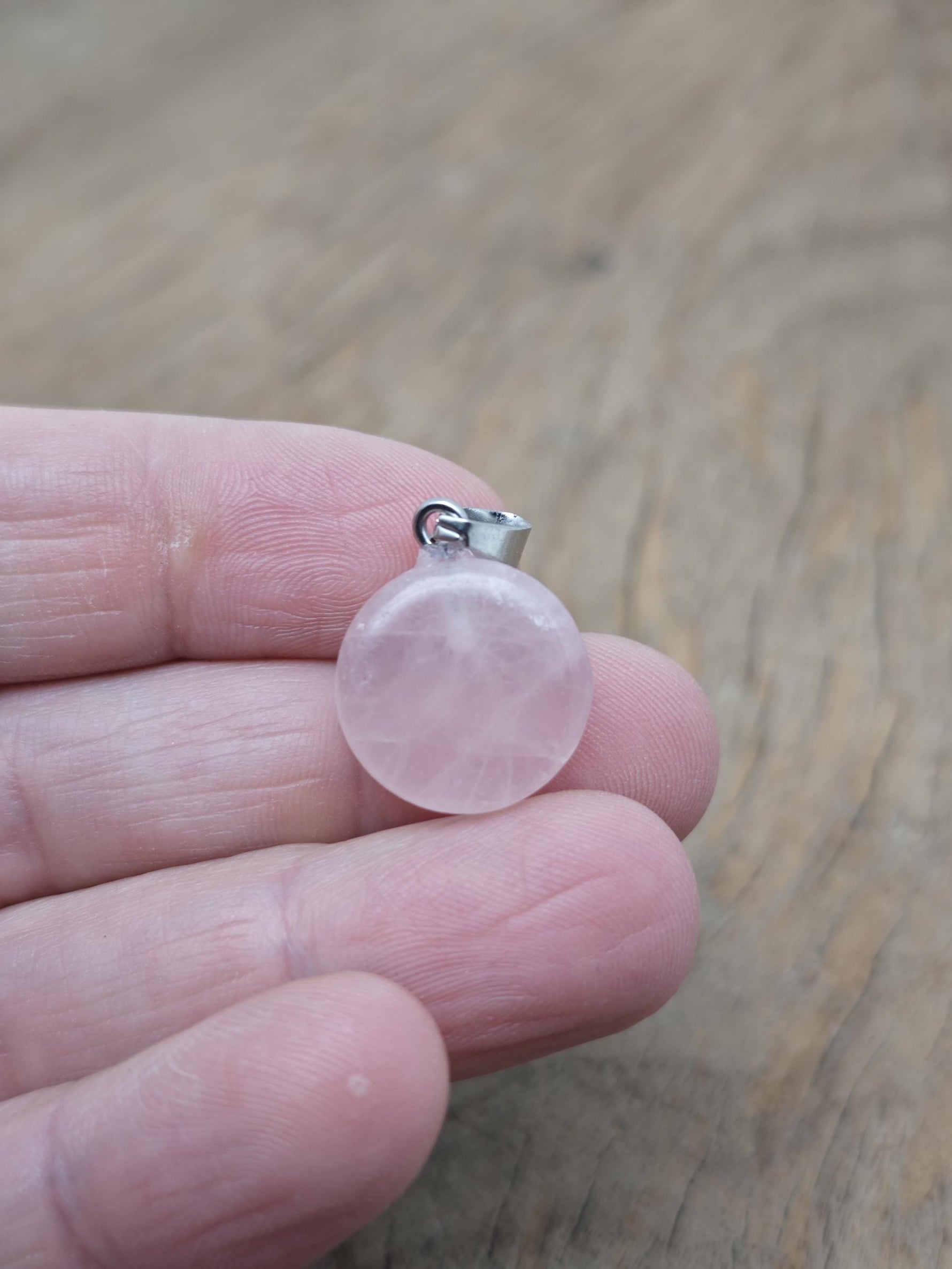 Rose quartz flat round gemstone pendant with a crystal coin design, showcasing a smooth, polished pink gemstone on a silver setting.