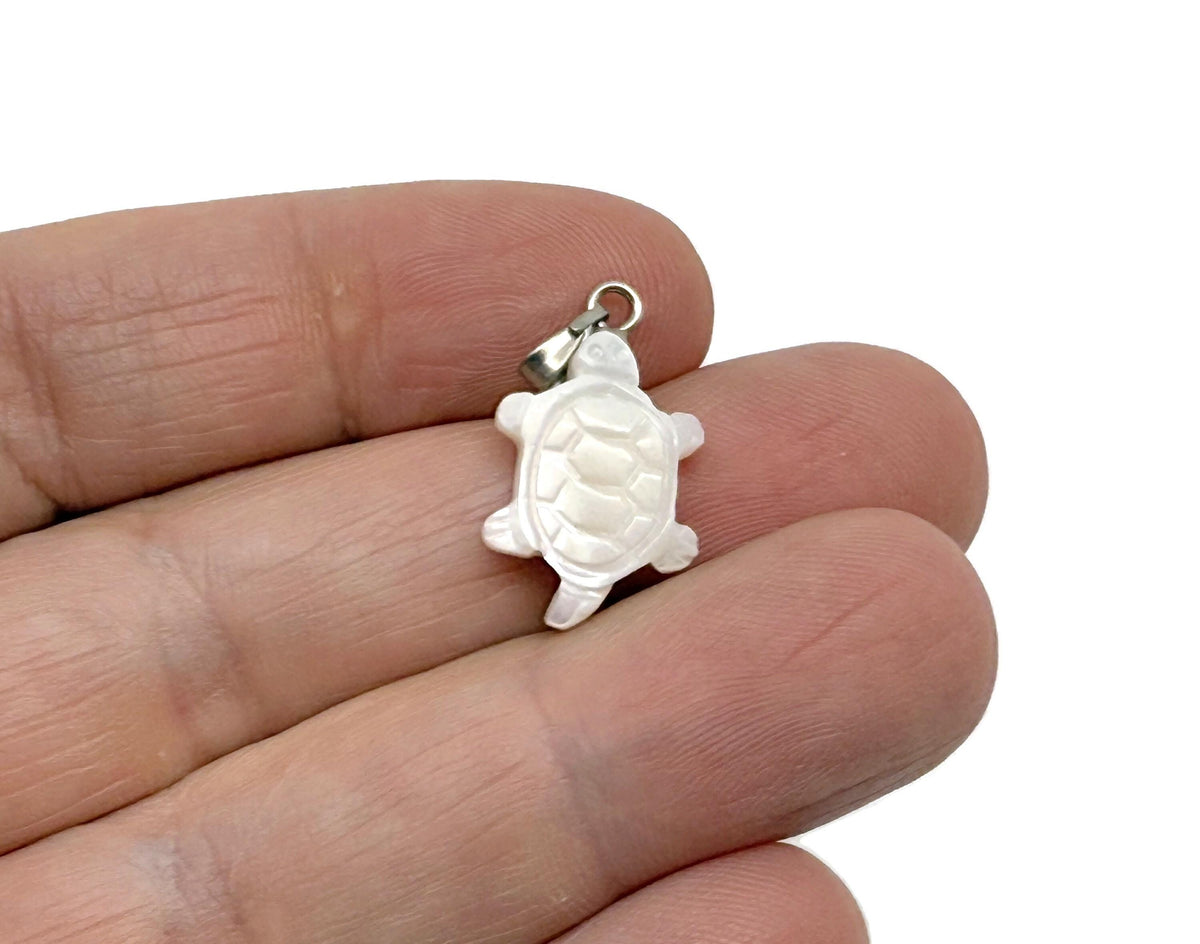 Natural pearl and tortoise shell pendant with gemstone accents, showcasing a delicate jewelry design on a neutral background.