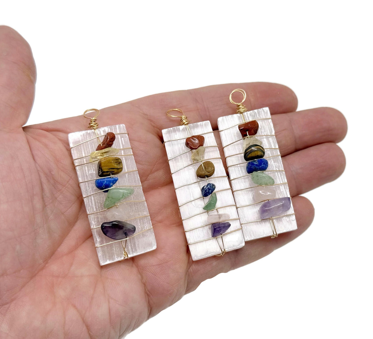 Selenite sticks pendant with chakra stones and gemstone accents, hanging from a silver chain, showcasing natural mineral textures.