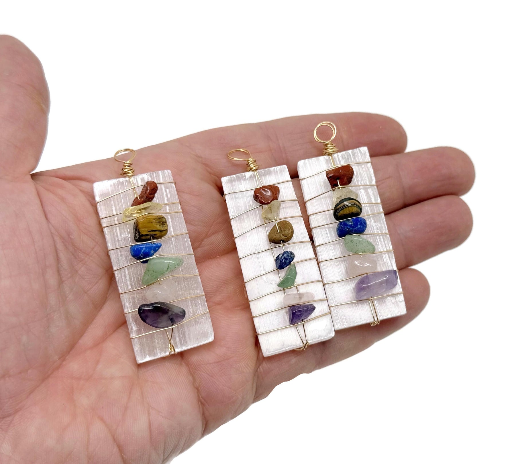 Selenite sticks pendant with chakra stones and gemstone accents, hanging from a silver chain, showcasing natural mineral textures.