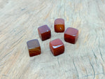 Handmade 16mm carnelian cube stone from GemstoneGO, featuring carved details and vibrant orange-red color.