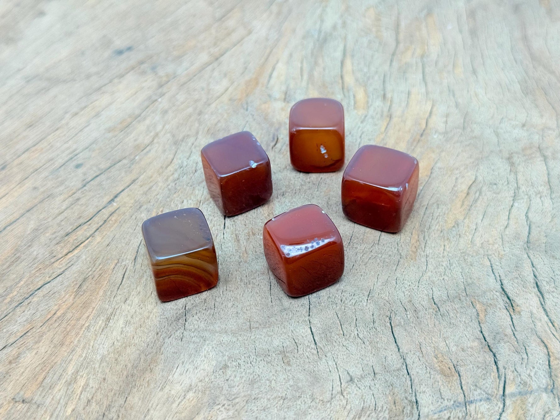 Handmade 16mm carnelian cube stone from GemstoneGO, featuring carved details and vibrant orange-red color.
