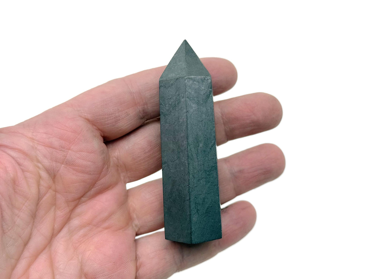 Shungite obelisk tower crystal from GemstoneGO, smooth black stone with natural texture and pointed top, standing upright.