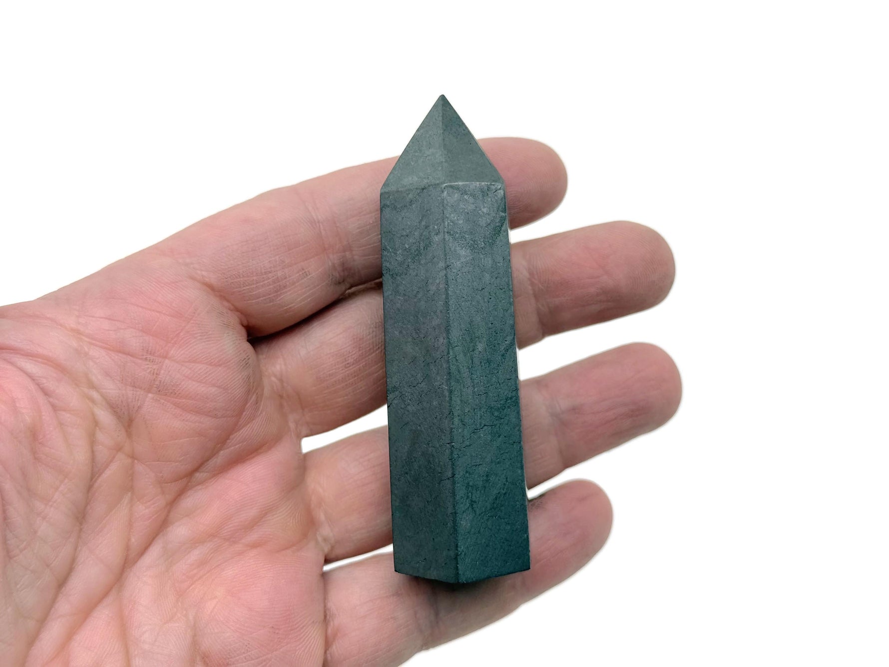 Shungite obelisk tower crystal from GemstoneGO, smooth black stone with natural texture and pointed top, standing upright.