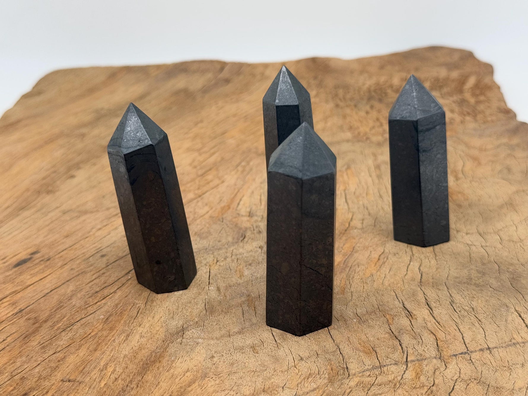 Shungite obelisk tower crystal from GemstoneGO, featuring a black stone with a smooth, polished surface and pointed top.