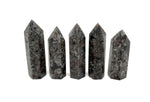 Yooperlite obelisk tower crystal featuring fluorescent sodalite stone with vibrant blue and purple hues, displayed against a neutral background.