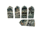 Ocean Jasper obelisk tower crystal by GemstoneGO, featuring vibrant green, orange, and cream patterns in a polished stone display.