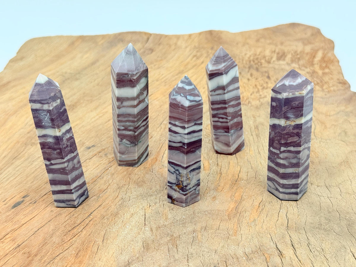 Red zebra calcite obelisk tower crystal from GemstoneGO, featuring vibrant red and white striped patterns and a pointed tip.
