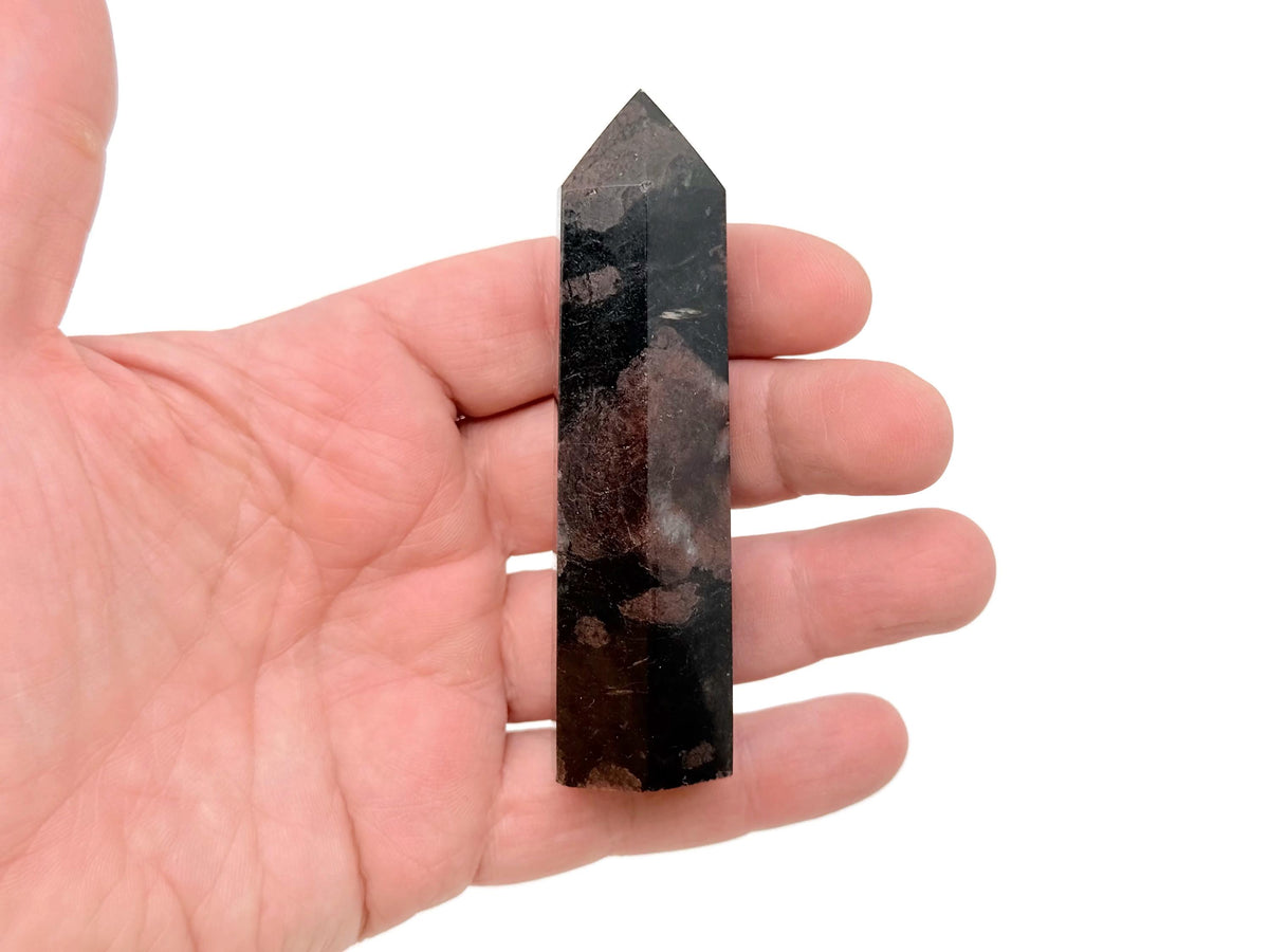 Garnet obelisk tower crystal from GemstoneGO, featuring a polished deep red gemstone with pointed geometric shape.